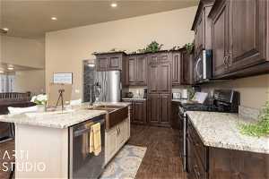 Kitchen featuring dark brown cabinetry, appliances with stainless steel finishes, sink, dark hardwood / wood-style floors, and a center island with sink