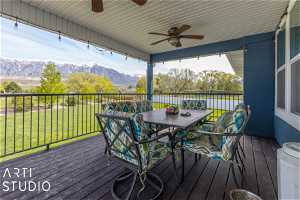 Deck featuring a mountain view, ceiling fan, and a lawn