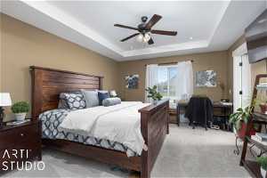 Carpeted bedroom with ceiling fan and a tray ceiling