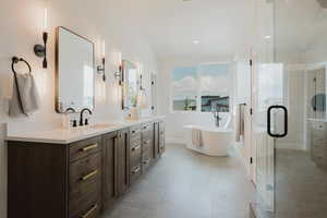 Bathroom featuring double vanity, a stall shower, and a freestanding bath