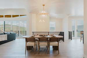 Dining area featuring wood finished floors, a chandelier, plenty of natural light, and vaulted ceiling