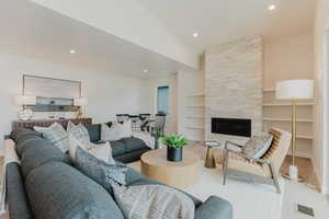 Living room featuring built in shelves, recessed lighting, a tile fireplace, and wood finished floors