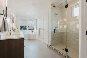 Bathroom with a stall shower, double vanity, and a freestanding tub