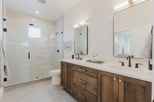 Full bathroom featuring double vanity, a stall shower, and tile patterned flooring