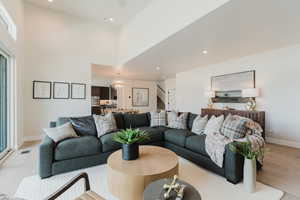 Living area featuring stairs, light wood-style floors, a chandelier, and recessed lighting