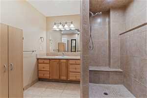 Bathroom with tile floors, vanity, and a tile shower