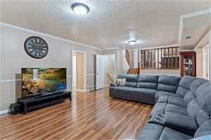 Living room with ornamental molding, a textured ceiling, and hardwood / wood-style floors