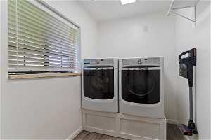 Washroom with dark hardwood / wood-style floors and independent washer and dryer