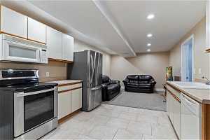 Kitchen featuring white cabinets, sink, appliances with stainless steel finishes, and light tile flooring