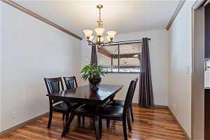 Dining room featuring dark hardwood / wood-style flooring, a chandelier, and crown molding