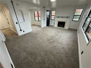 Unfurnished living room with plenty of natural light, carpet floors, and a fireplace