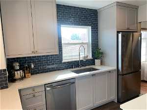 Kitchen featuring sink, tasteful backsplash, stainless steel appliances, and dark wood-type flooring