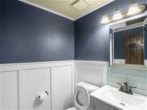 Bathroom with ornamental molding, tasteful backsplash, toilet, and oversized vanity