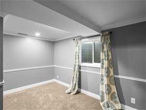 Carpeted empty room featuring ornamental molding