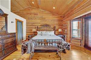 Bedroom featuring lofted ceiling, light hardwood / wood-style floors, rustic walls, and wood ceiling
