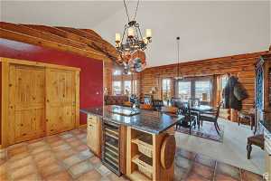 Kitchen featuring log walls, vaulted ceiling, wine cooler, and an inviting chandelier