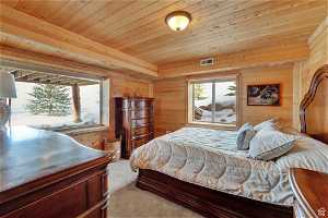 Carpeted bedroom featuring wood ceiling and wood walls