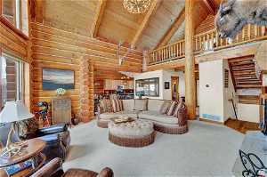 Living room with high vaulted ceiling, log walls, carpet, and wood ceiling