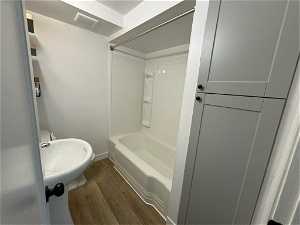 Full bathroom with hardwood / wood-style flooring, toilet, shower / washtub combination, and sink