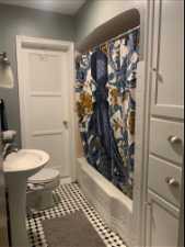 Bathroom featuring shower / bath combo with shower curtain, toilet, and tile flooring