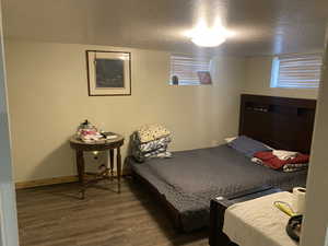 Bedroom with a textured ceiling and dark hardwood / wood-style flooring