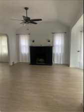 Unfurnished living room featuring lofted ceiling, plenty of natural light, ceiling fan, and light hardwood / wood-style flooring