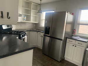 Kitchen featuring plenty of natural light, appliances with stainless steel finishes, tasteful backsplash, and white cabinets