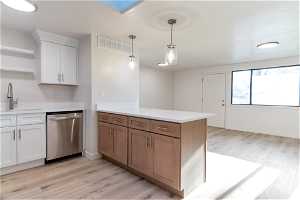 Kitchen with light hardwood (LVP) / wood-style flooring, sink, dishwasher, and decorative light fixtures