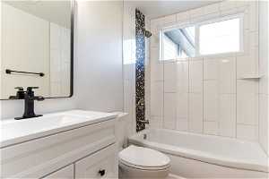 Full bathroom with large vanity, toilet, and tiled shower / bath