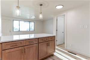 Kitchen featuring light hardwood  (LVP)/ wood-style floors and decorative light fixtures
