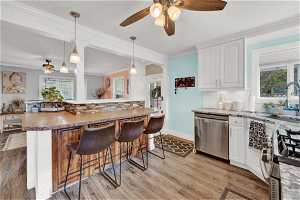Kitchen featuring stove, white cabinetry, tasteful backsplash, light hardwood / wood-style floors, and dishwasher