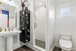 Bathroom featuring an Euro door to the shower, bidet attached toilet, metal locker, hardwood / wood-style flooring, and a pedestal sink