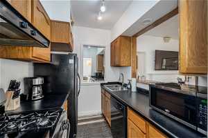 Kitchen featuring fume extractor, black dishwasher, rail lighting, sink, and gas range oven