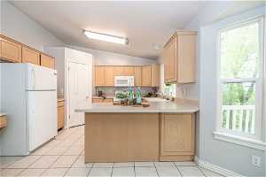 Kitchen with plenty of natural light, light brown cabinets, white appliances, light tile flooring, and sink