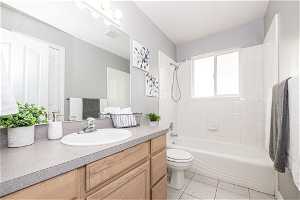 Full bathroom with tile floors, vanity, tiled shower / bath combo, and toilet