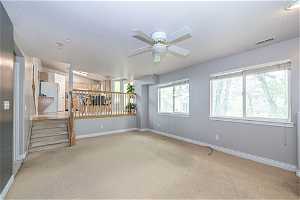 Spare room with a textured ceiling, ceiling fan, and carpet