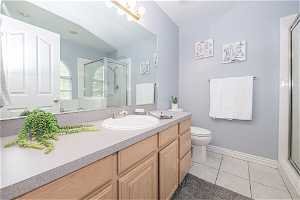 Bathroom featuring an enclosed shower, toilet, tile floors, and large vanity
