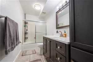 Full bathroom featuring toilet, combined bath / shower with glass door, tile flooring, and vanity
