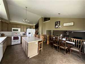 Kitchen with a center island, white appliances, backsplash, tile flooring, and vaulted ceiling