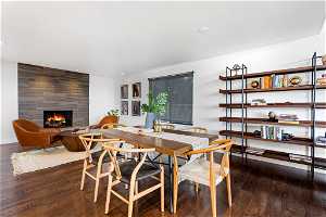 Dining area with tile walls, dark hardwood / wood-style floors, and a tile fireplace
