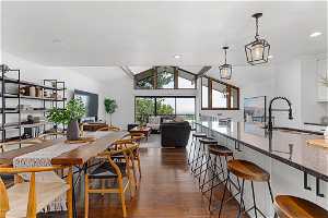 Dining space featuring dark hardwood / wood-style floors, sink, lofted ceiling with beams, and an inviting chandelier