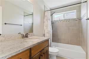 Full bathroom featuring vanity, shower / bathtub combination with curtain, and toilet