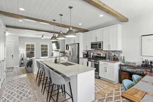 Kitchen with pendant lighting, appliances with stainless steel finishes, beam ceiling, and a kitchen bar