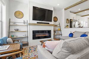 Living room with a large fireplace, hardwood / wood-style floors, and beam ceiling