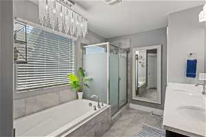 Primary Bathroom with tile floors, separate shower and tub, mirror, and his and her basins