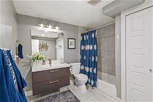 Full bathroom with tile floors, bathing tub / shower combination, mirror, vanity, toilet, and shower curtain