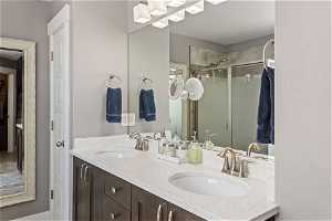 Primary Bathroom with mirror, shower with shower door, and dual large vanity