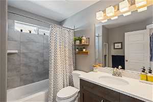 Full bathroom with mirror, toilet, vanity with extensive cabinet space, shower curtain, and bathing tub / shower combination