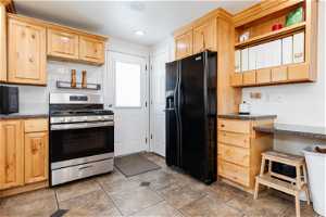 Kitchen featuring light brown cabinets, tile floors, and black appliances