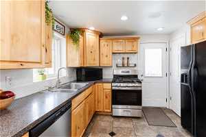 Kitchen featuring light brown cabinets, sink, backsplash, tile floors, and black appliances